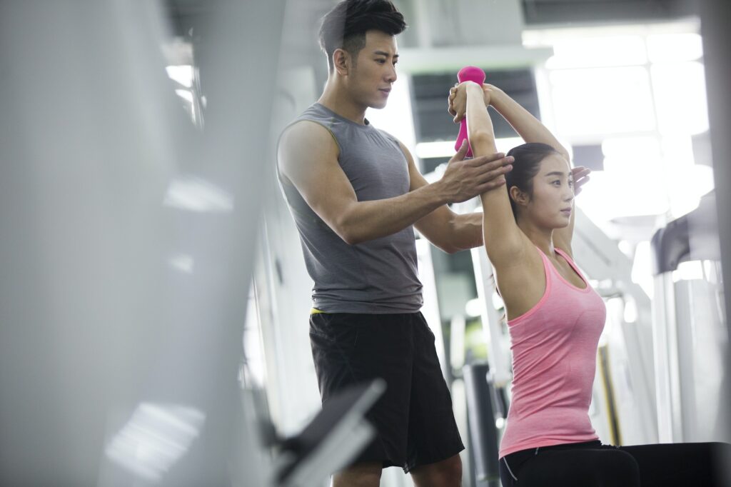 Young woman working with trainer at gym